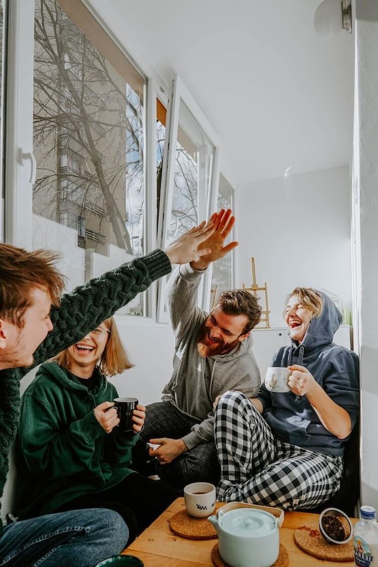 friends sitting down in a room givinh hi five at  a tea party