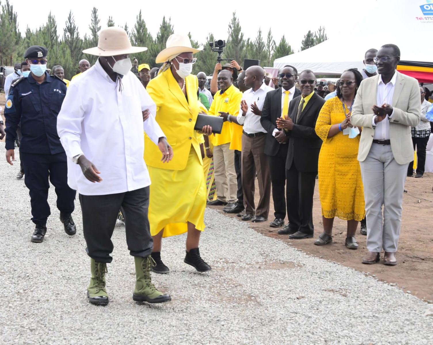 Museveni walking with his wife on stonny ground