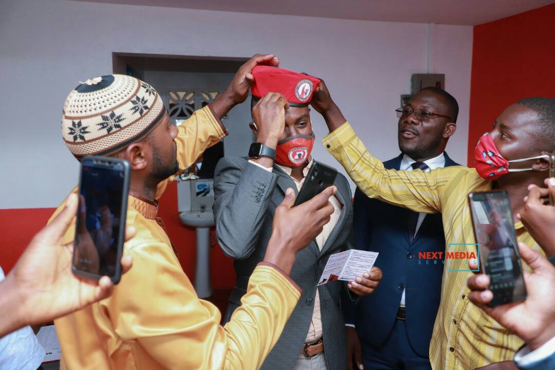 A happy Andrew Mwenda gets initiated into people power by wearing their famous red beret