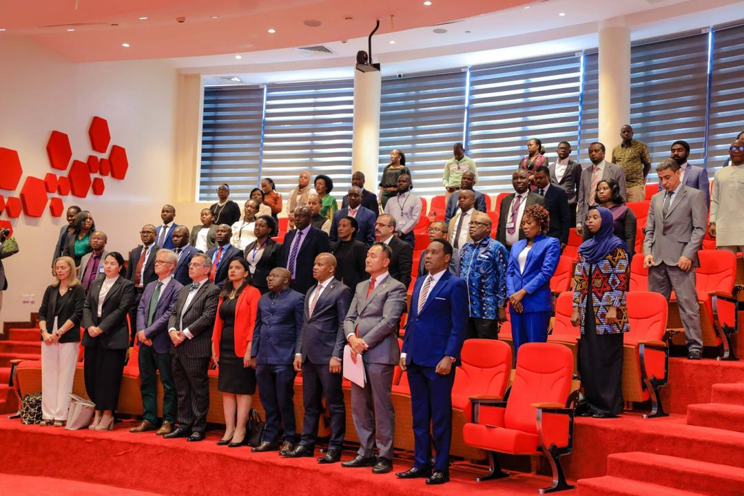 The meeting in progress, members stand next to their seats in an auditorium