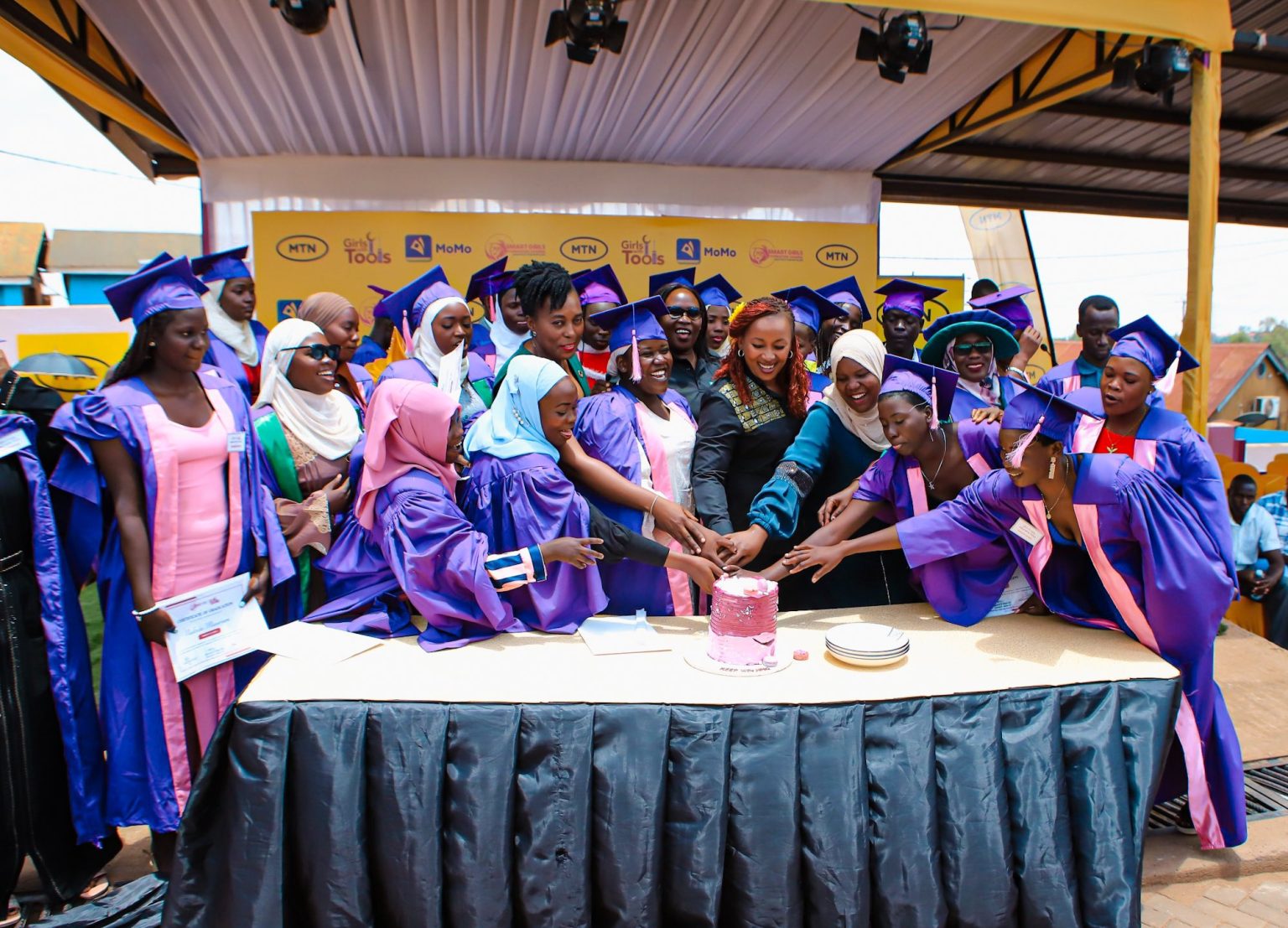 MTN Girls in graduation gowns cut cake together with CEO Sylvia Mulinge